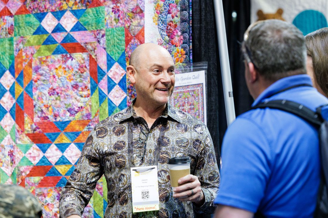 A maker reaching for a wall of embroidery thread