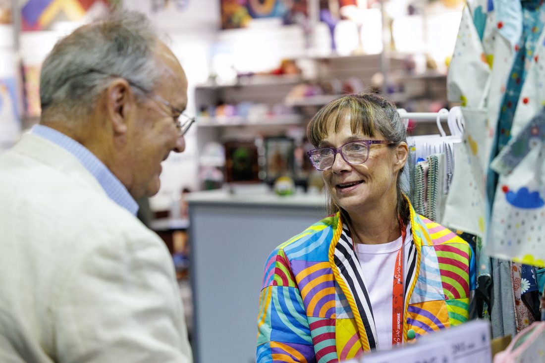 Two attendees laughing at a sewing machine demo