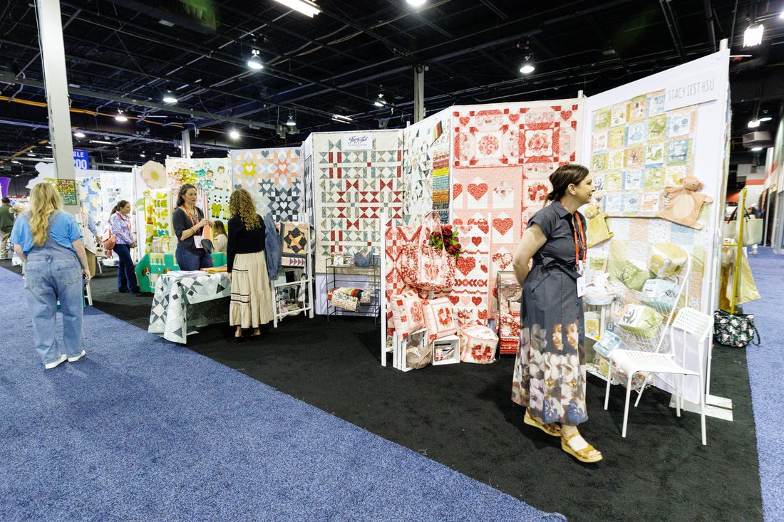 Shoppers browsing a colorful quilt booth