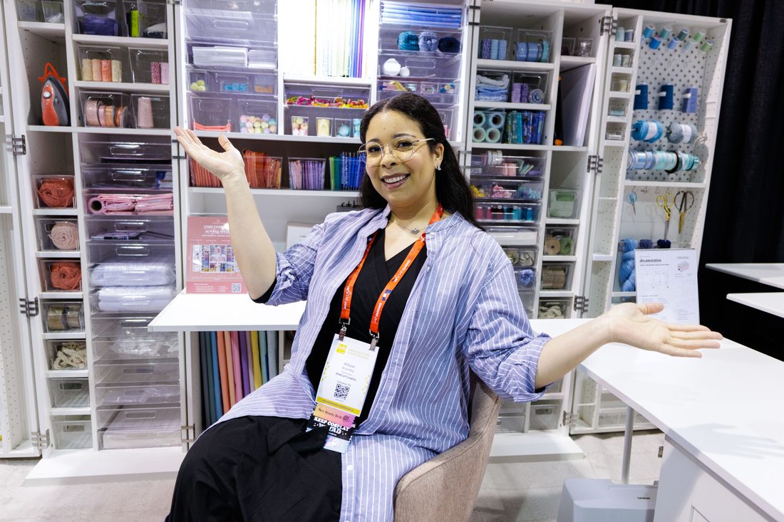 A presenter gesturing toward a wall of yarn